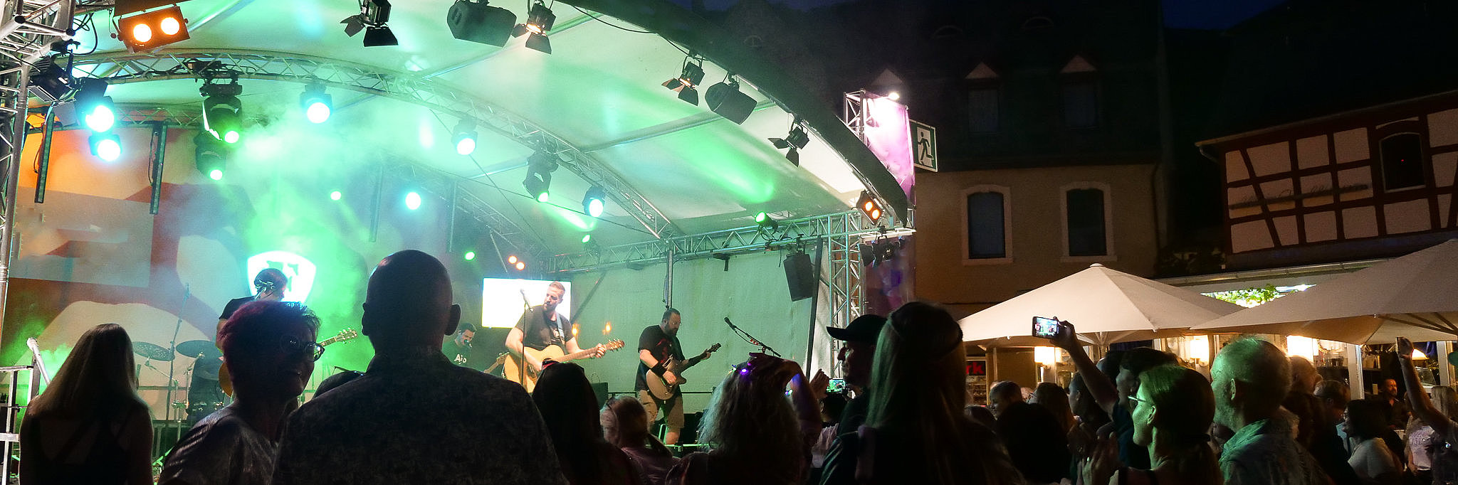 Livemusik auf dem Weinfest der Mittelmosel in Bernkastel-Kues Auf dem Bild eine ausgelassene Menschenmenge vor einer Bühne auf dem Karlsbalder Platz. Das Konzert findet abends statt.