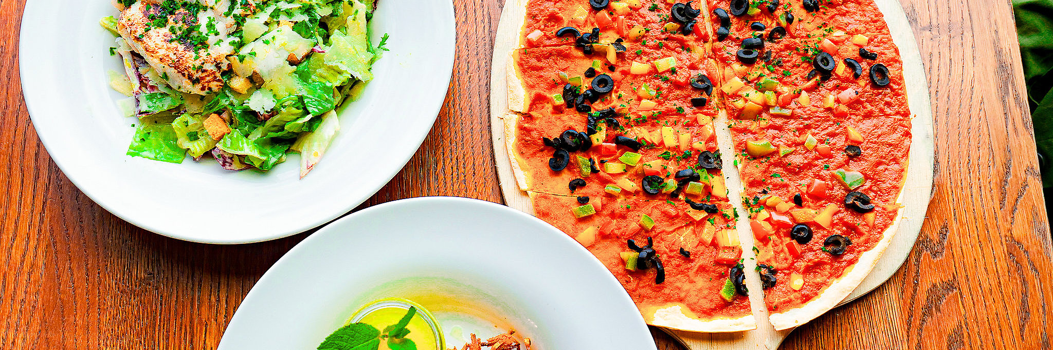 Dreierlei kulinarische Köstlichkeiten Das Foto zeigt drei kulinarische Gerichte. Bei einem Gericht handelt es sich um Salat mit Putenbruststreifen. Ebenso sieht man einen Flammkuchen mit Oliven und einen moselfränkischen Auflauf mit Apelmus.