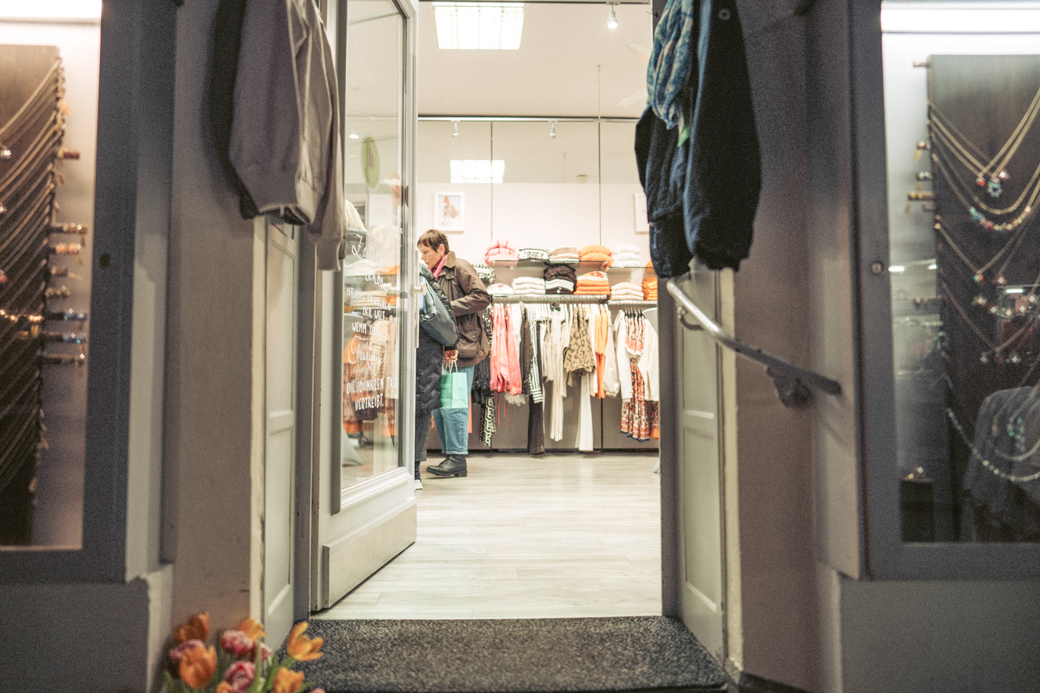 Shoppen in Bernkastel-Kues Blick durch die offene Tür eines Bekleidungsgeschäft am Abend. Eine Frau schaut sich im Geschäft die Auslage an.